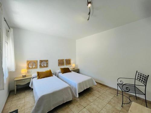 two beds in a white room with a table and chairs at HOTEL MUSEO Lucainena in Lucainena de las Torres