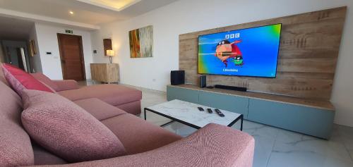 a living room with two pink couches and a flat screen tv at Horizon Residence in Ix-Xagħra taʼ Barra