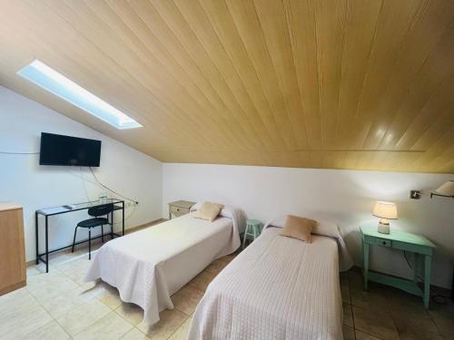 a room with two beds and a desk and a television at HOTEL MUSEO Lucainena in Lucainena de las Torres
