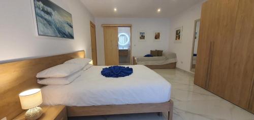 a bedroom with a white bed with a blue flower on it at Horizon Residence in Ix-Xagħra taʼ Barra