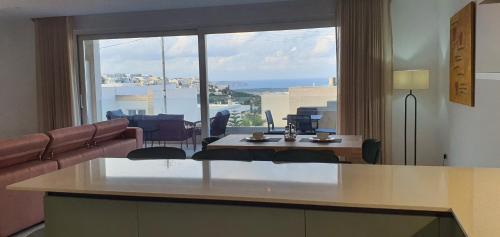 a living room with a table and a large window at Horizon Residence in Ix-Xagħra taʼ Barra
