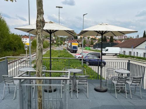 a patio with tables and chairs and umbrellas at Übernachten im nostalgischen Bahnwaggon in Bogen