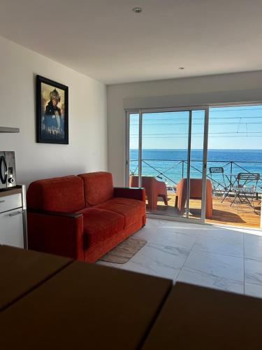 - un salon avec un canapé rouge et une vue sur l'océan dans l'établissement La Pitchounette bord de mer, à Cannes