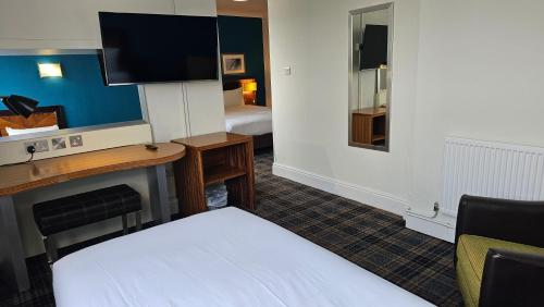 a hotel room with a bed and a desk with a television at Hampstead Britannia in London