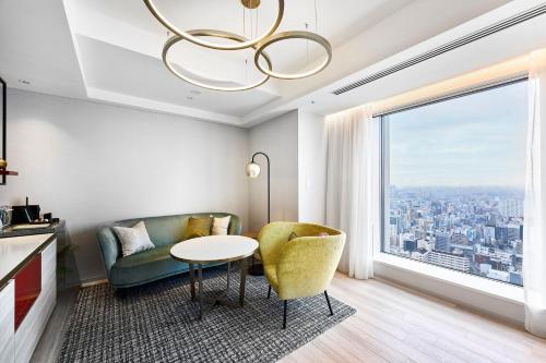 a living room with a table and a couch and a window at Centara Grand Hotel Osaka in Osaka
