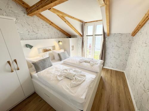 a bedroom with a white bed in a room with wooden floors at Haus Seeblick mit 9 Wohnungen in Alt Reddevitz