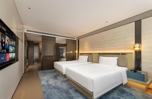 a hotel room with two beds and a tv at Shanghai Hongqiao Heyitang Hotel Beixinjing Subway Station Branch in Shanghai