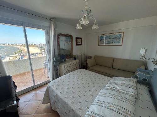 a bedroom with a bed and a couch and a window at Superbe appartement 2 chambres face à la mer au Grau du Roi l'Impérial in Le Grau-du-Roi