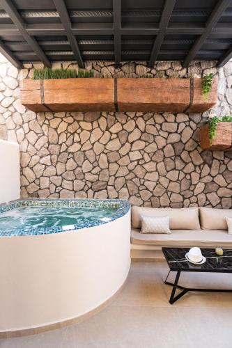 a hot tub in a room with a stone wall at The Cosmopolitan - Karterados Urban Suites in Karterados