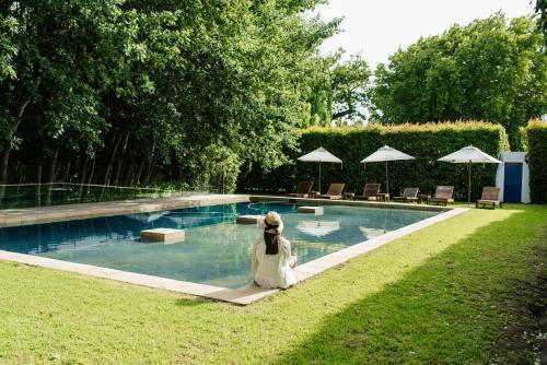 a woman is sitting next to a swimming pool at La Paris Estate in Franschhoek