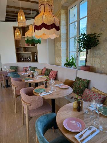 a restaurant with wooden tables and chairs and windows at Sainte Raphine in Fargues-Saint-Hilaire
