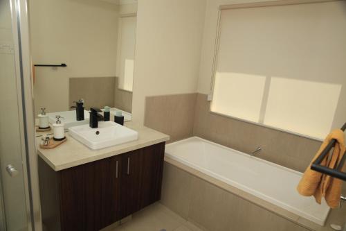 a bathroom with a sink and a bath tub at Family Home in Truganina in Truganina