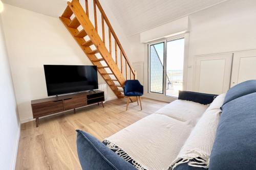 a living room with a bed and a tv and a staircase at Duplex plein charme Face mer & déco moderne in Quiberon