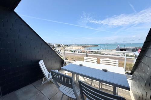 a table and chairs on a balcony with a view of the beach at Duplex plein charme Face mer & déco moderne in Quiberon