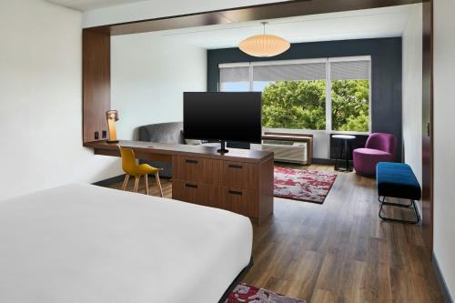 a hotel room with a bedroom with a bed and a television at Aloft Raleigh in Raleigh