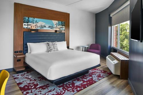 a bedroom with a white bed and a window at Aloft Raleigh in Raleigh