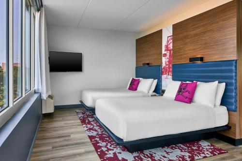 a hotel room with two beds and a flat screen tv at Aloft Raleigh in Raleigh