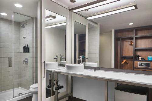 a bathroom with two sinks and a shower at Aloft Raleigh in Raleigh