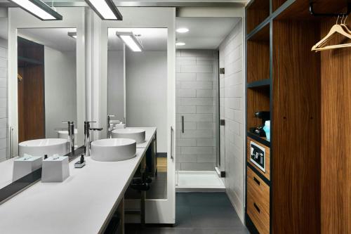 a bathroom with three sinks and two mirrors at Aloft Raleigh in Raleigh