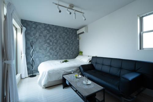 a room with a bed and a couch and a table at Park side stay Shinjuku in Tokyo