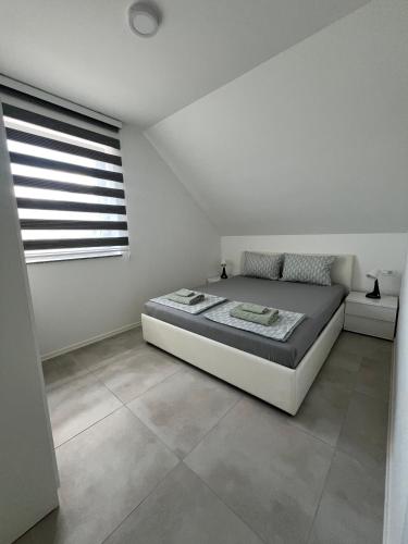 a white bedroom with a bed and a window at Natura Apartments in Kranj