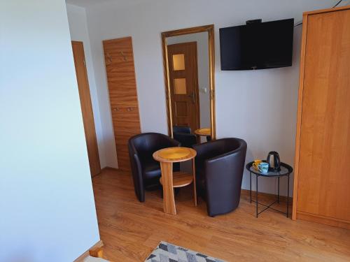 a room with two chairs and a table and a television at Dom Gościnny Sawinka in Polańczyk