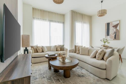 ein Wohnzimmer mit zwei Sofas und einem Tisch in der Unterkunft Nasma - RAK Bliss 2BR Villa, Maid Room & Backyard in Ras al Khaimah