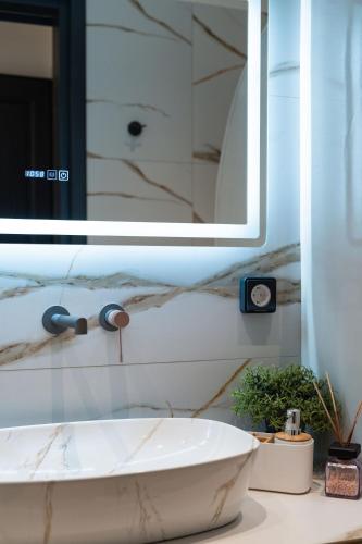 a bathroom with a sink and a mirror at The Cosmopolitan - Karterados Urban Suites in Karterados
