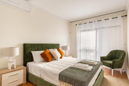a bedroom with a large bed and a green chair at 3BR Apt w Balcony and Sea View in Cascais