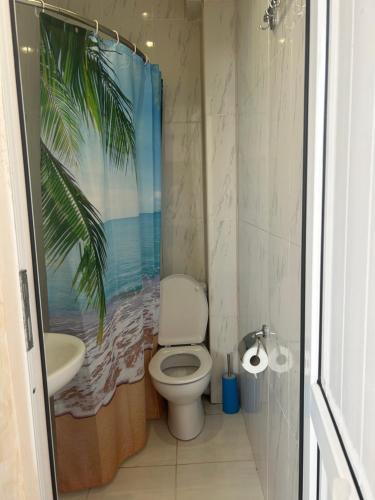 a bathroom with a toilet and a palm tree shower curtain at Hotel George in Ureki