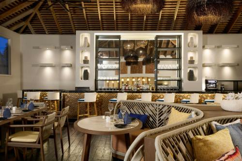 a restaurant with tables and chairs and a bar at Waves Resort & Spa, Barbados, An Autograph Collection All-Inclusive Resort in Saint James