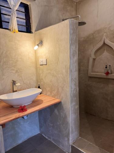 a bathroom with a white bowl sink on a wooden counter at Paje By Night Bungalows in Paje