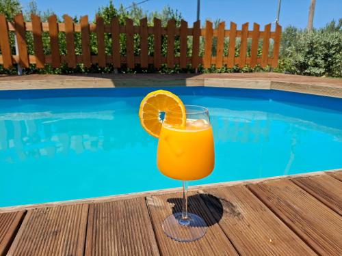 a glass of orange juice sitting on a table near a swimming pool at Terra Solaris Guesthouse in Kissamos
