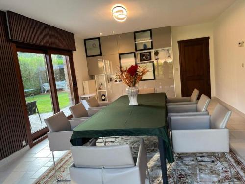 a dining room with a green table and white chairs at Villa op de hoek Rooms in Aalst