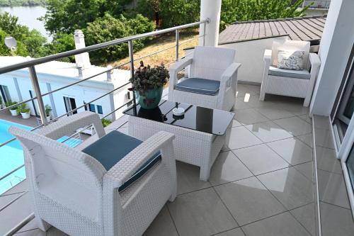 a balcony with white chairs and a table and a table and chairs at Apartments Villa Graf in Smederevo