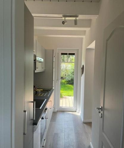 a kitchen with a hallway leading to a door with a window at Ferienhaus Deich Huus in Kappeln