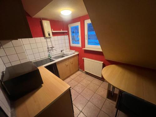 a kitchen with red walls and a sink and a table at Siegen Monteuren Wohnung 6 in Siegen