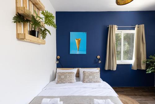 a bedroom with blue walls and a bed with pillows at Rena's House - Beach Edition in Tel Aviv