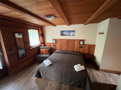 a bedroom with a bed and two chairs in it at Villa Americana Chambres d'Hotes in Champoluc