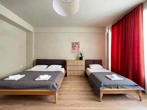 2 Betten in einem Zimmer mit roten Vorhängen in der Unterkunft Lomi's Homey - Rooms in Tbilisi City