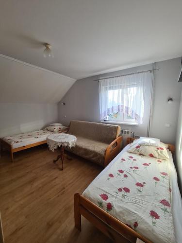 a bedroom with two beds and a couch and a window at Pokoje gościnne u Ewy Cisna in Cisna