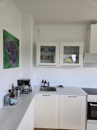 a white kitchen with white cabinets and a sink at Charmerende og hyggelig lejlighed tæt på centrum in Viby