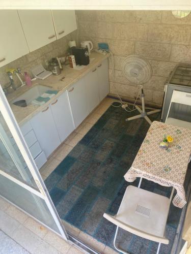 a small kitchen with a table and a sink at דירת גן מרווחת במיקום מעולה עם נטפליקס חינמי in Ma'ale Adumim