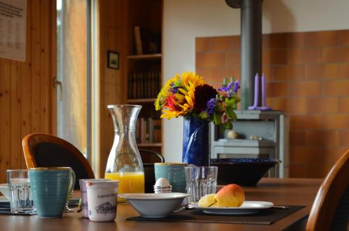 un tavolo con un vaso di fiori e un vaso di succo d'arancia di Appartement Vue Neuve a Corgémont