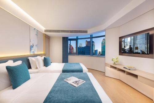 a hotel room with two beds and a large window at Oakwood Central Wuxi in Wuxi