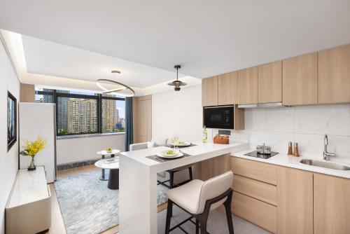 a kitchen with a counter and a kitchen island with chairs at Oakwood Central Wuxi in Wuxi