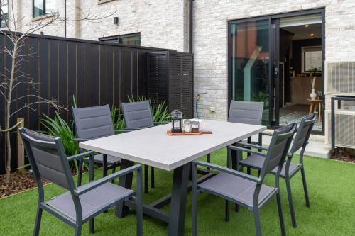ein Tisch und Stühle auf einer Terrasse mit Rasen in der Unterkunft Spacious 2BR, 2Bath Home Base on Gloucester Street in Christchurch