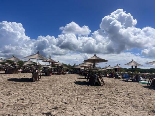 a beach with straw umbrellas and chairs on the sand at Gjiri Lalezit Swimming Pool Beach Villa in Lalëz