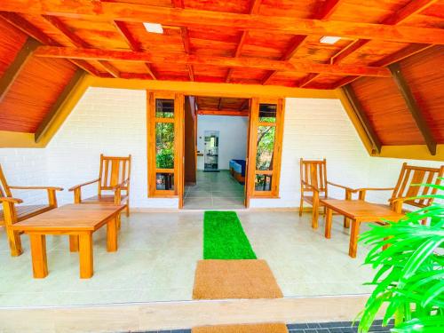 a porch with wooden chairs and a green lawn at Lotus Eco Villa in Sigiriya