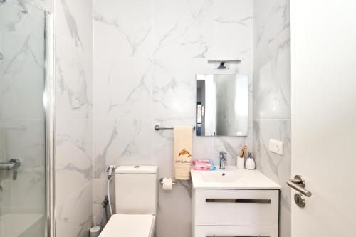 a white bathroom with a toilet and a sink at Apartamentos Golfinho Dourado in Santa Maria